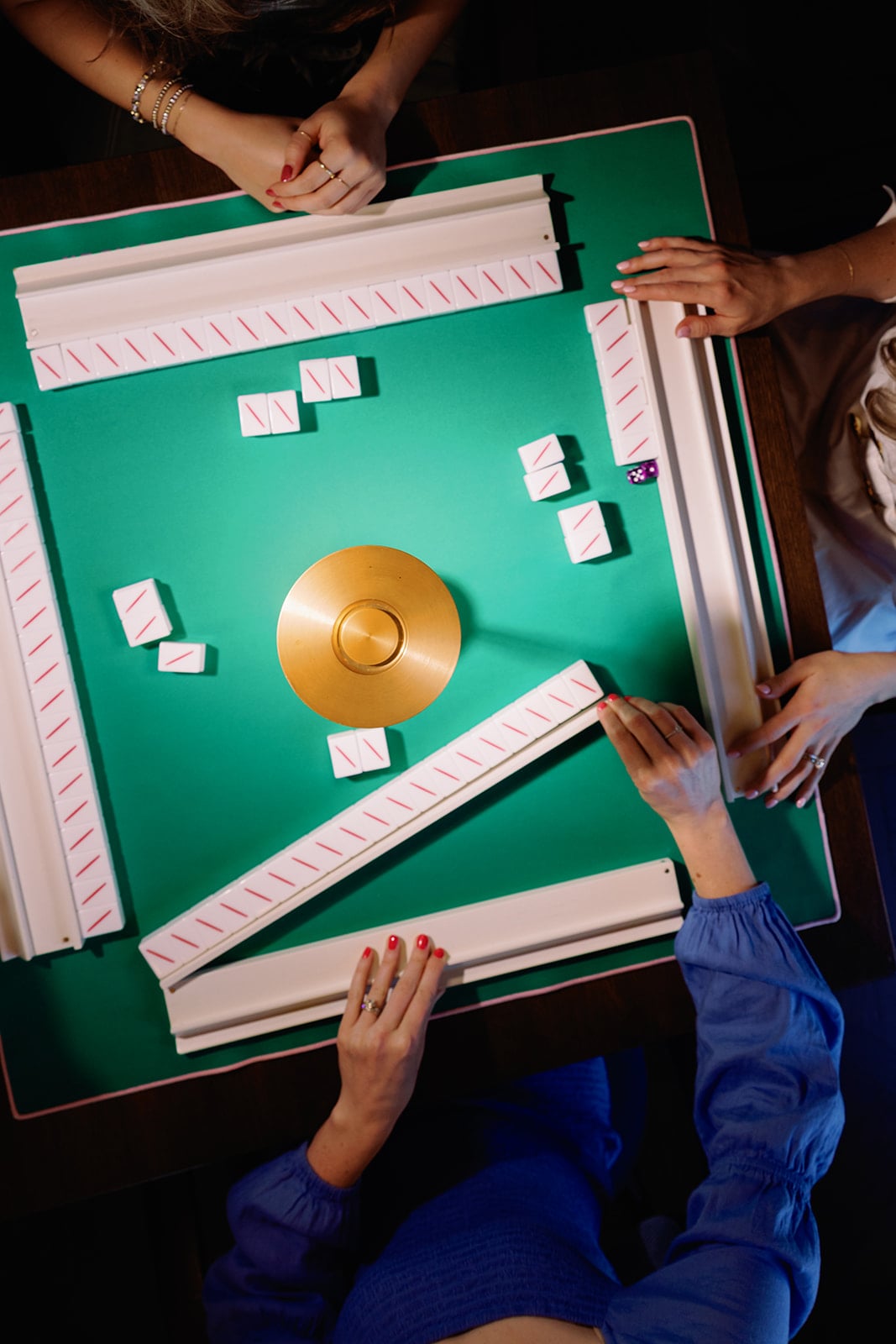 Four players beginning a mahjong game at a green table