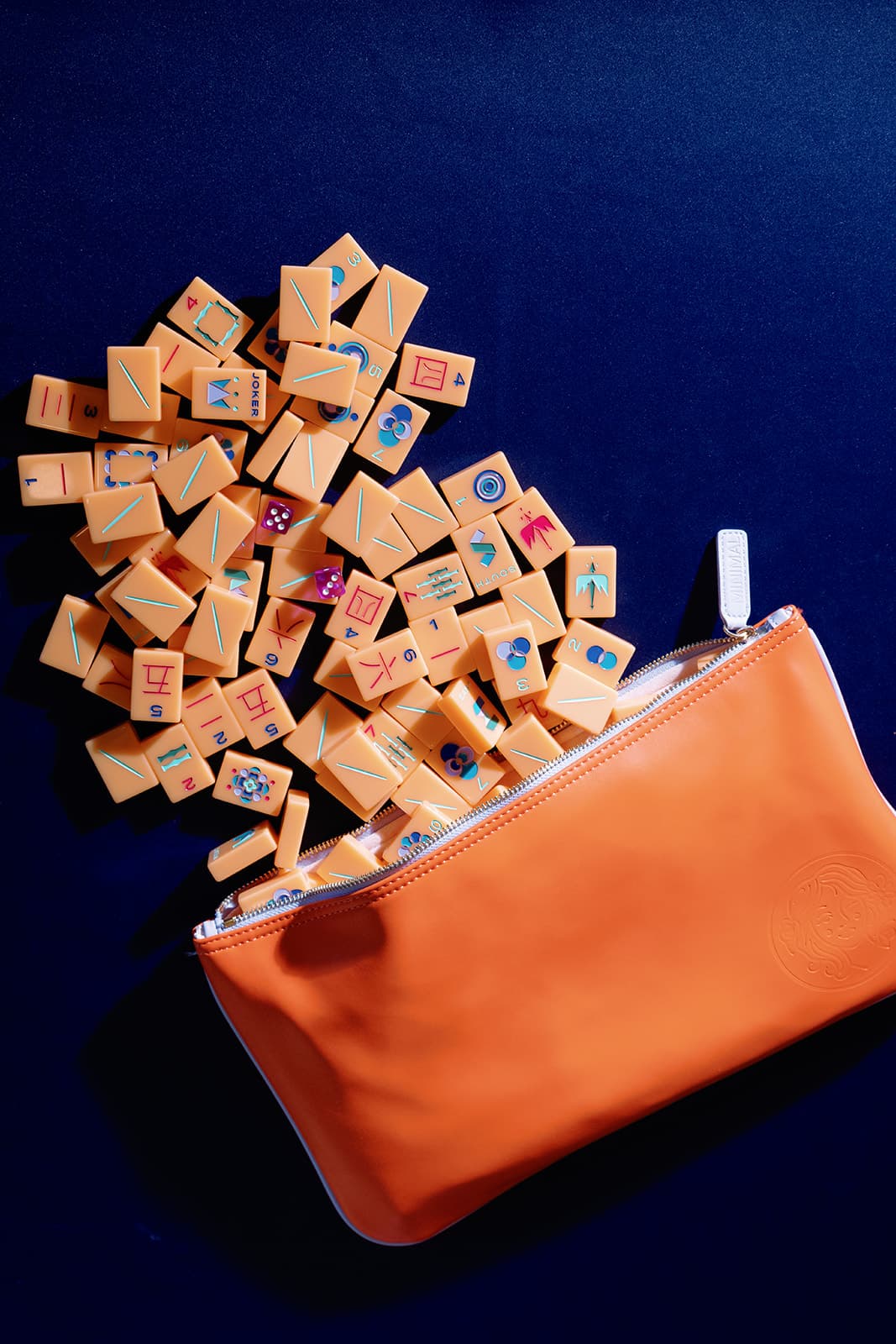 Orange mahjong tiles spilling from a zippered case